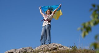 У рюкзаку через ворожі блокпости: жителька Херсона вивезла прапор з окупації й тепер мандрує з ним світом